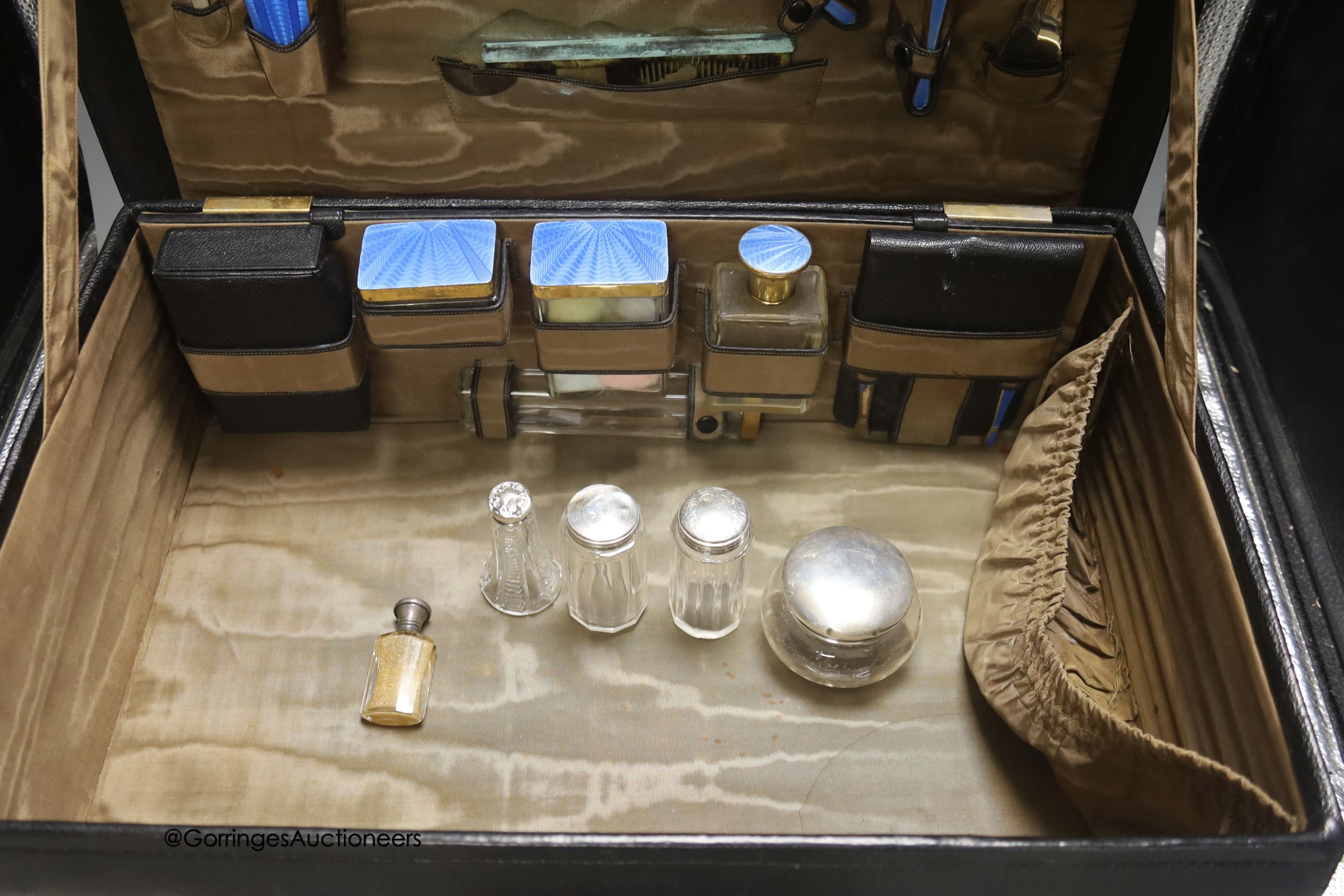 An early 20th century leather vanity case, with enclosed accessories and five further silver mounted vanity bottles